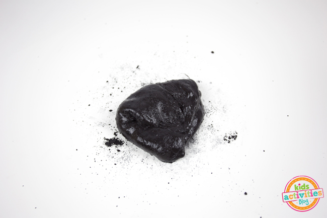 Étape 4 - comment faire du slime magnétique - du slime pétri avec de la poudre noire autour sur la surface de fond blanc