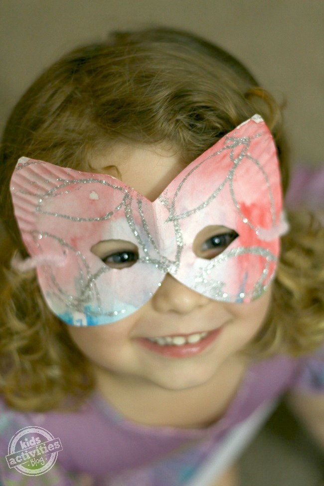Masques en assiettes en papier Craft - Masque en assiettes en papier avec du rouge, du vert, du bleu et des étincelles porté par une petite fille