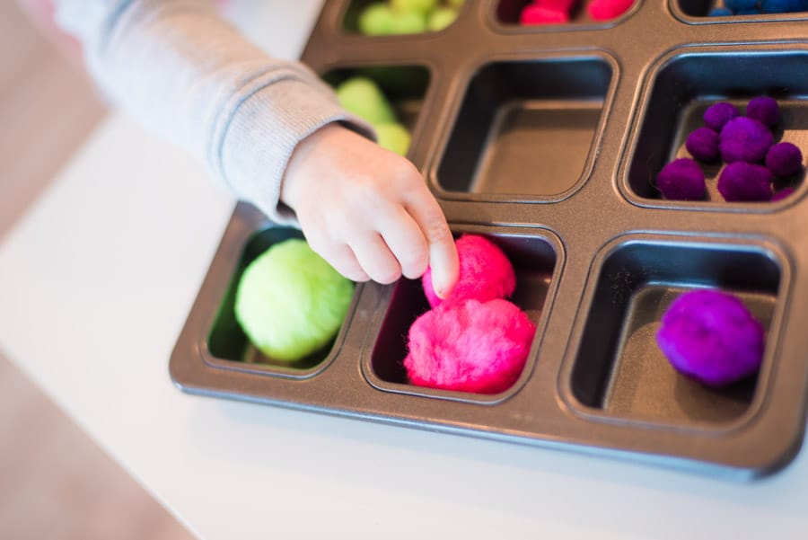 trier les pompons par couleur dans un moule à muffins de Hands on As We Grow