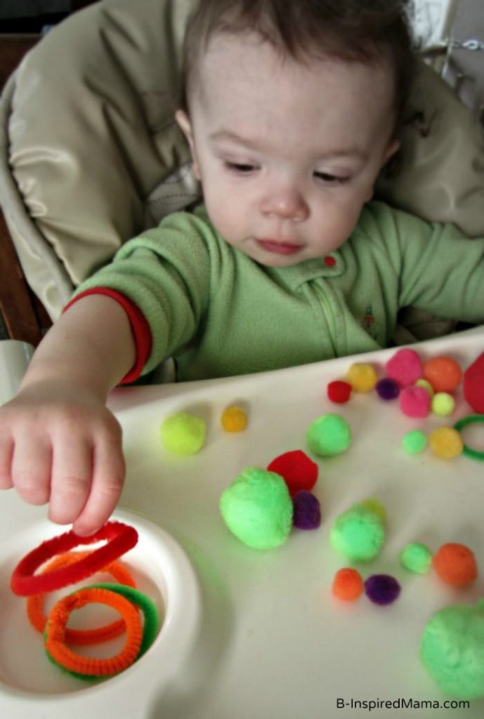 des cercles de pompons et de cure-pipes jouent sur une chaise haute avec bébé