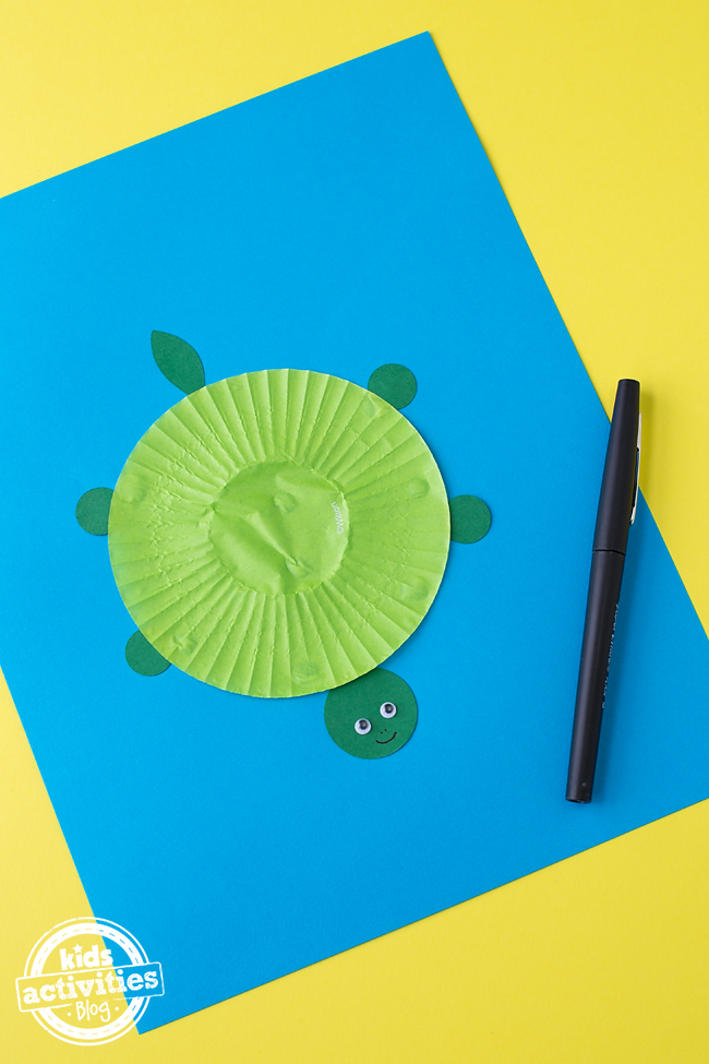 Cupcake Liner Turtle - étape 3 - ajoutez 2 yeux écarquillés à la tête de la tortue et dessinez 2 points pour le nez et le visage souriant - blog d'activités pour enfants