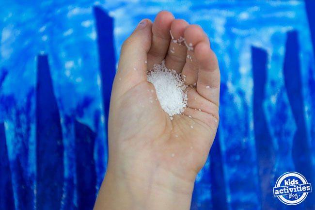 Winter Forest Preschool Art - Blog d'activités pour enfants - Enfant tenant du sel sur l'art du bâton de peinture