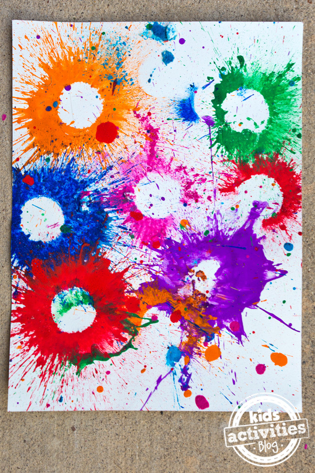 Texte : Bombes de peinture explosives - Blog d'activités pour enfants - Toile avec des éclaboussures d'orange, de bleu, de vert, de rose, de rouge et de violet