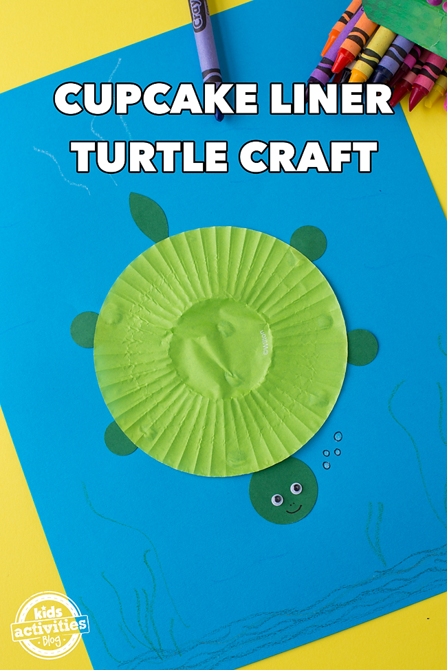 Cupcake Liner Tortue artisanale avec corps de doublure de cupcake, pattes, tête et queue en papier de construction, yeux écarquillés, sur du papier bleu coloré avec des crayons sur fond jaune - blog d'activités pour enfants