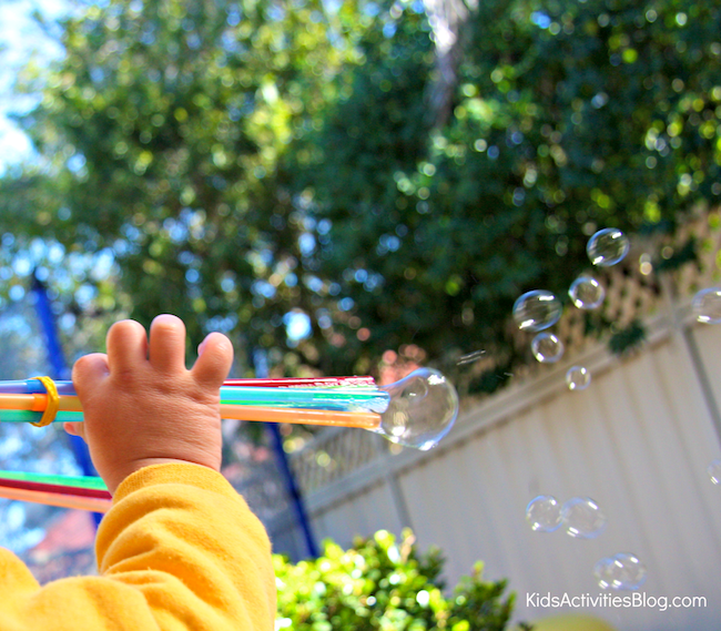 petit enfant à l'aide d'un lanceur de bulles pour souffler des bulles à travers la clôture de l'arrière-cour