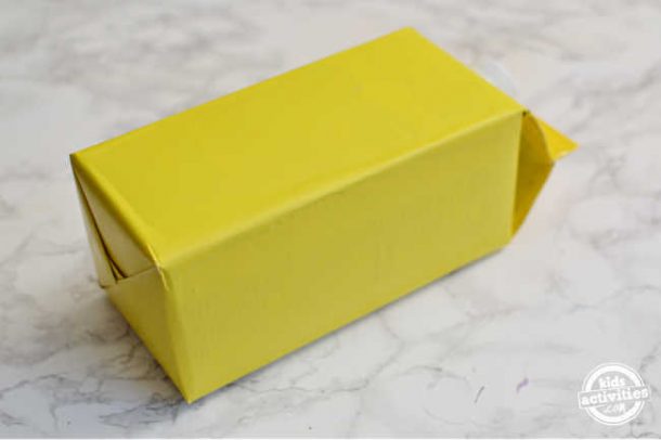 Étape 1 - Comment faire une boîte de la Saint-Valentin qui ressemble à un autobus scolaire - couvrez le carton de lait avec du papier d'emballage pour la boîte de la Saint-Valentin de l'autobus scolaire