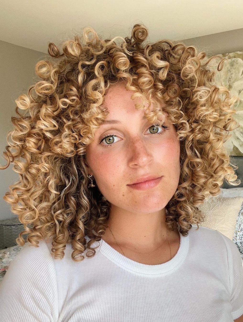 Femme aux cheveux bouclés avec une coupe en couches et une frange ouverte