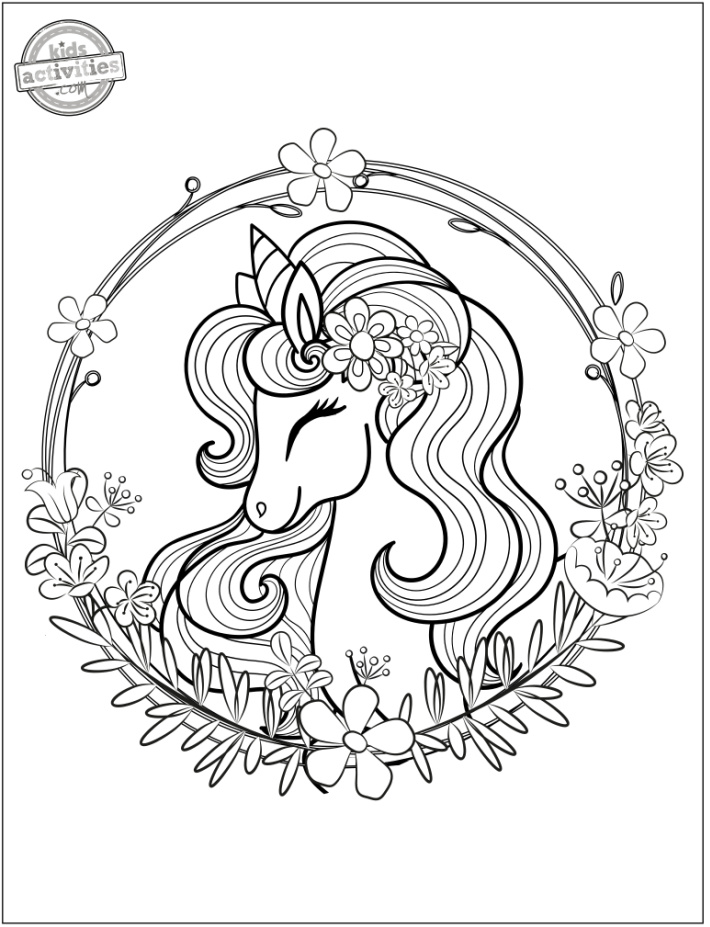Tête de licorne dans une couronne de fleurs à colorier - Blog d'activités pour enfants - page de coloriage gratuite imprimable pdf illustrée avec une couronne de fleurs entourant la tête de licorne avec des cheveux de licorne fluides