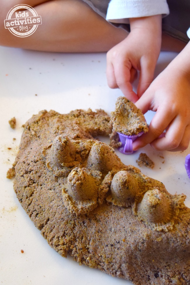 Sable cinétique bricolage fait avec du slime et du sable paly. Il est joué avec des jouets en plastique violet par de petites mains.