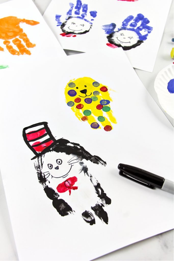 Cat in the Hat art réalisé à partir d'empreintes de mains et de peinture du blog d'activités pour enfants présenté sur un livre blanc