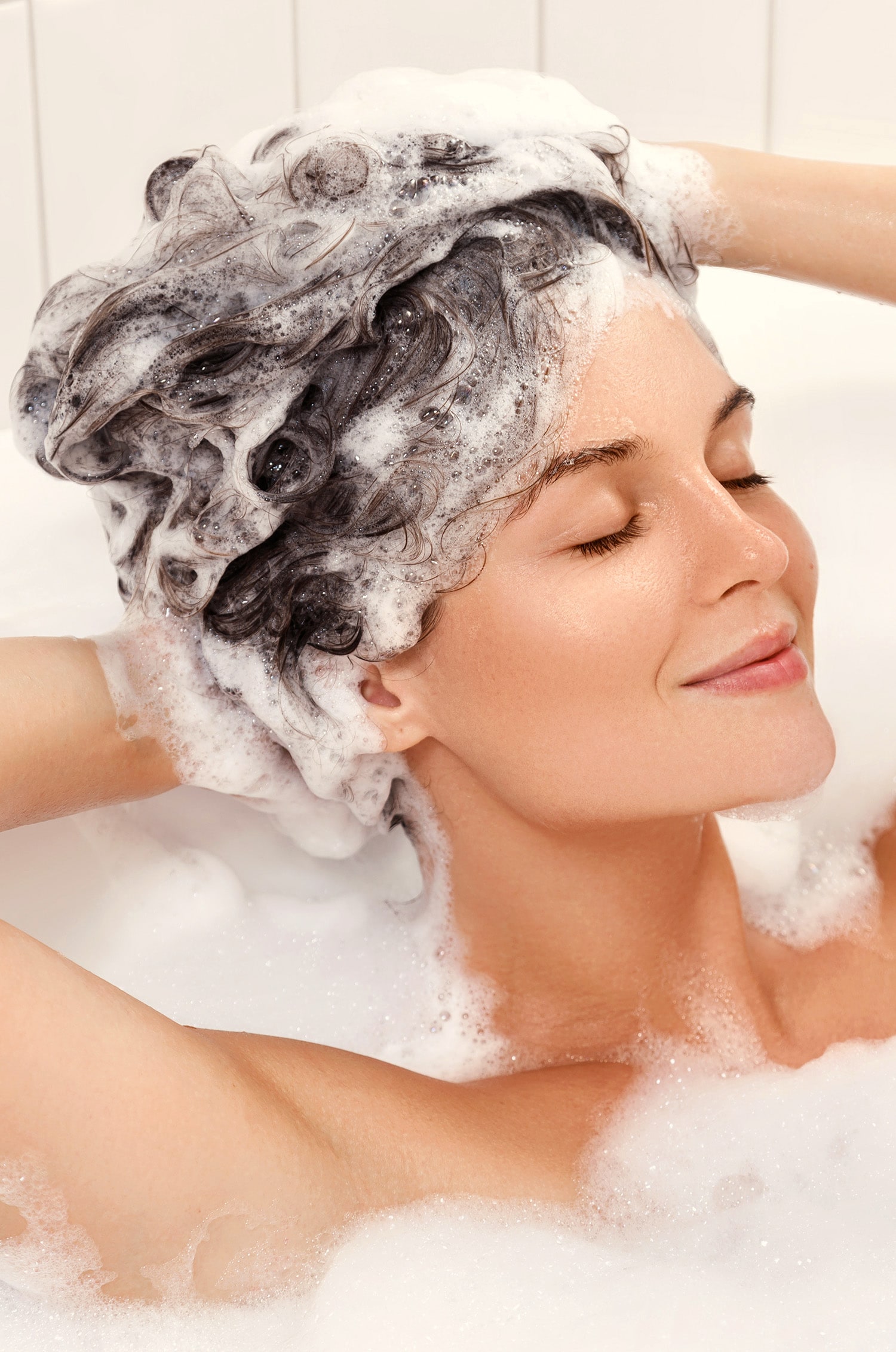 Femme se lavant les cheveux avec un shampoing aux vitamines pour les cheveux