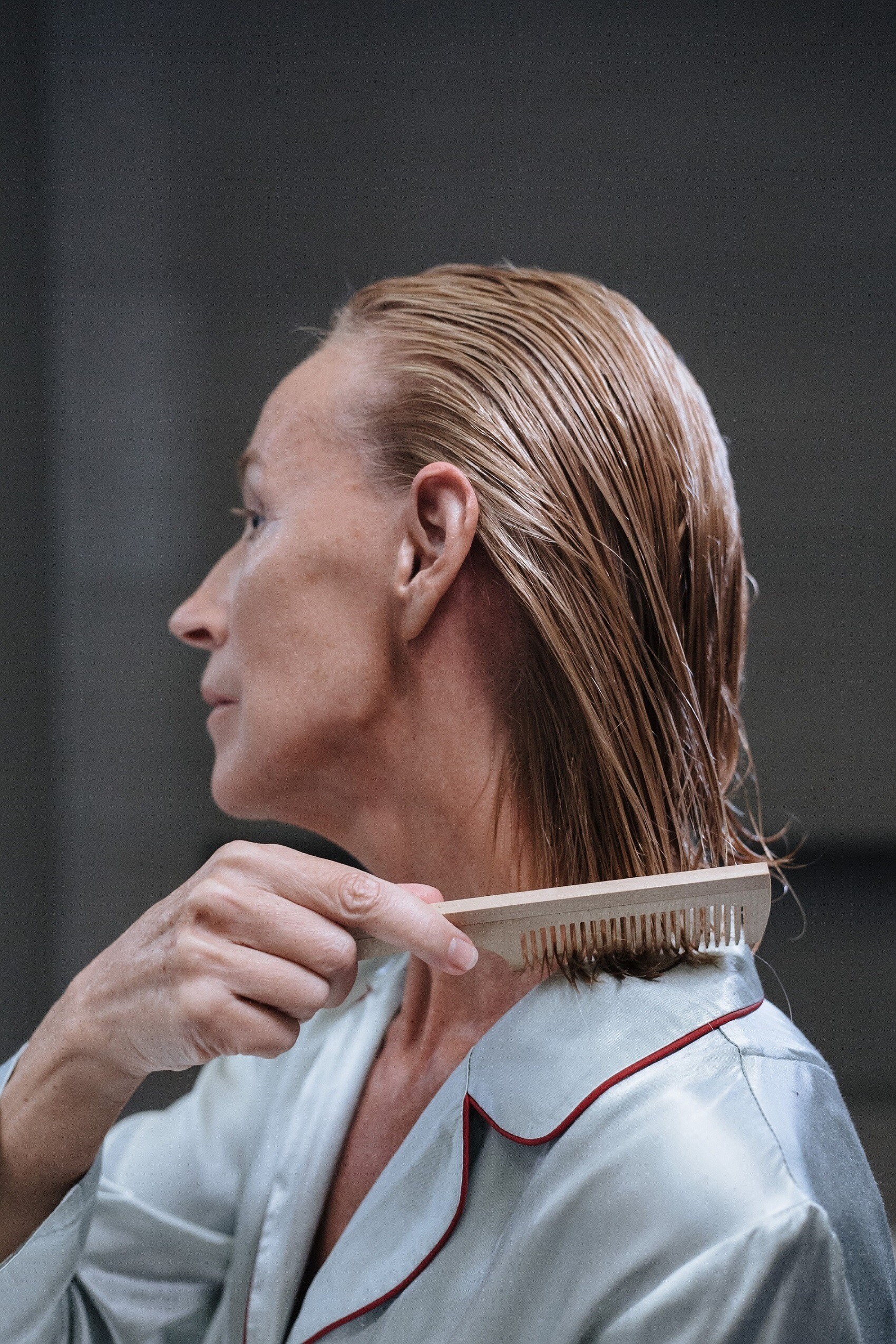 Femme démêlant ses cheveux mouillés avec un peigne en bois