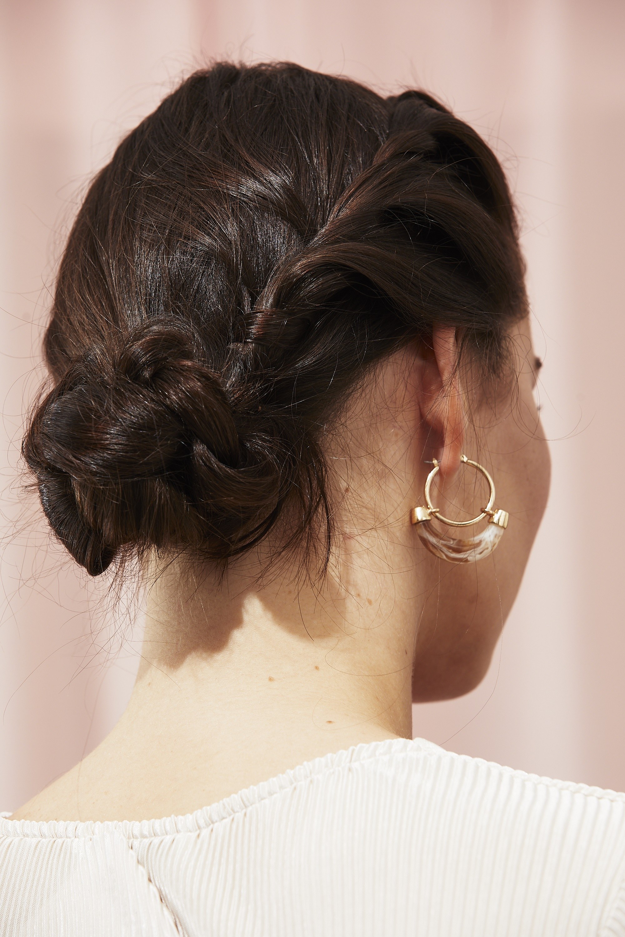 Femme avec un chignon bas tressé et une mèche roulée d'un côté