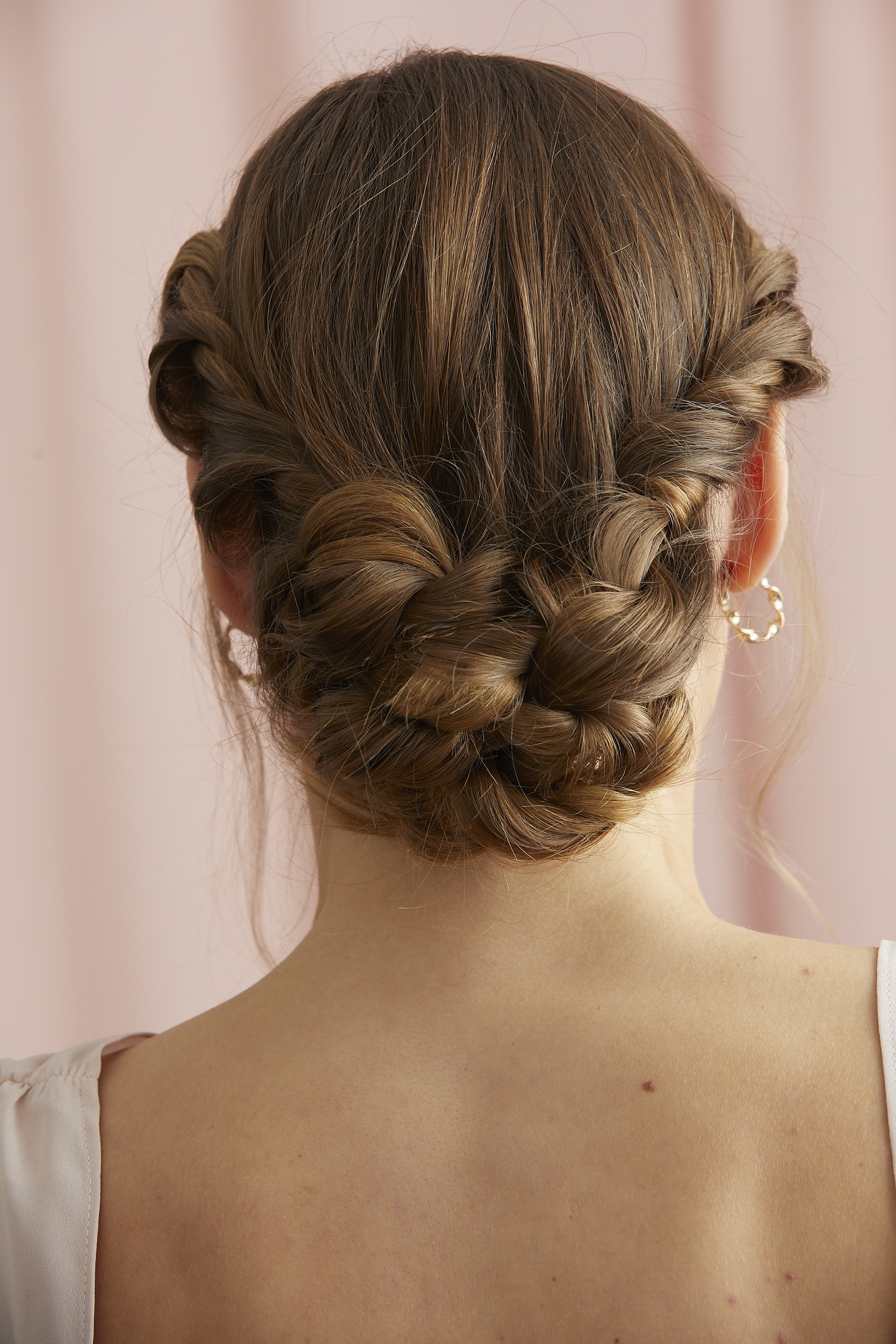 Femme avec un chignon bas tressé et des mèches bouclées devant