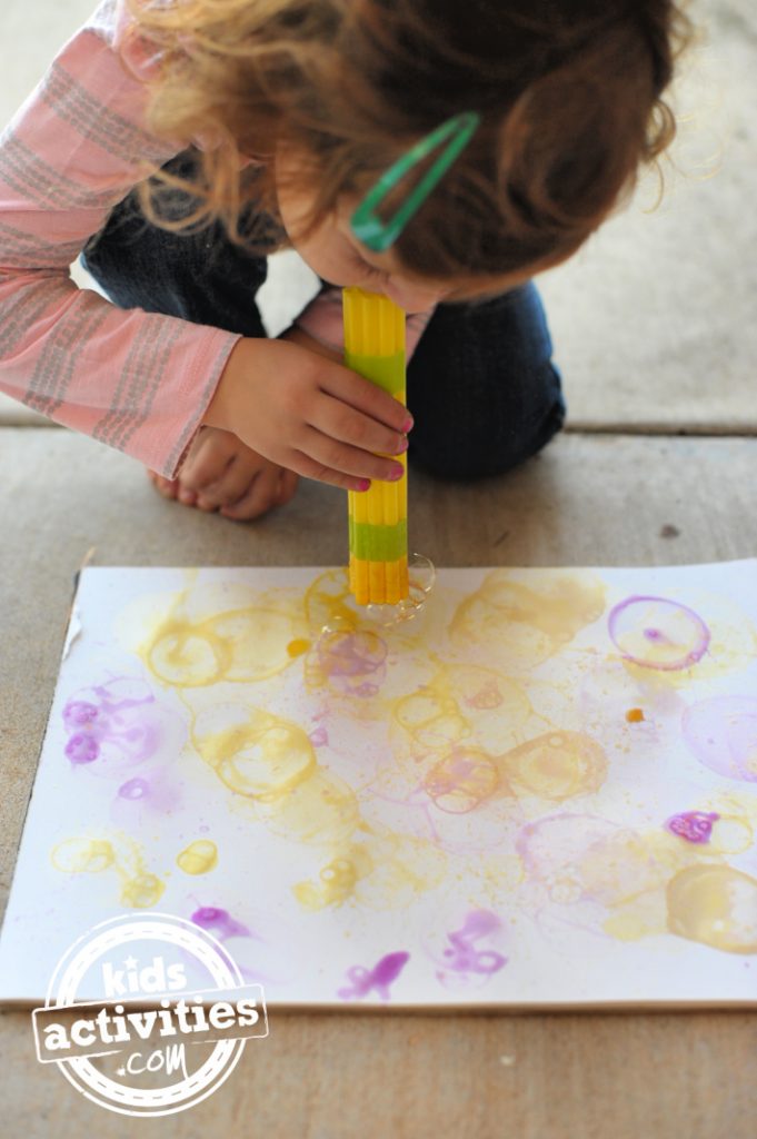 Enfant peignant avec des bulles à l'aide d'un lance-bulles directement sur du papier - Blog d'activités pour enfants