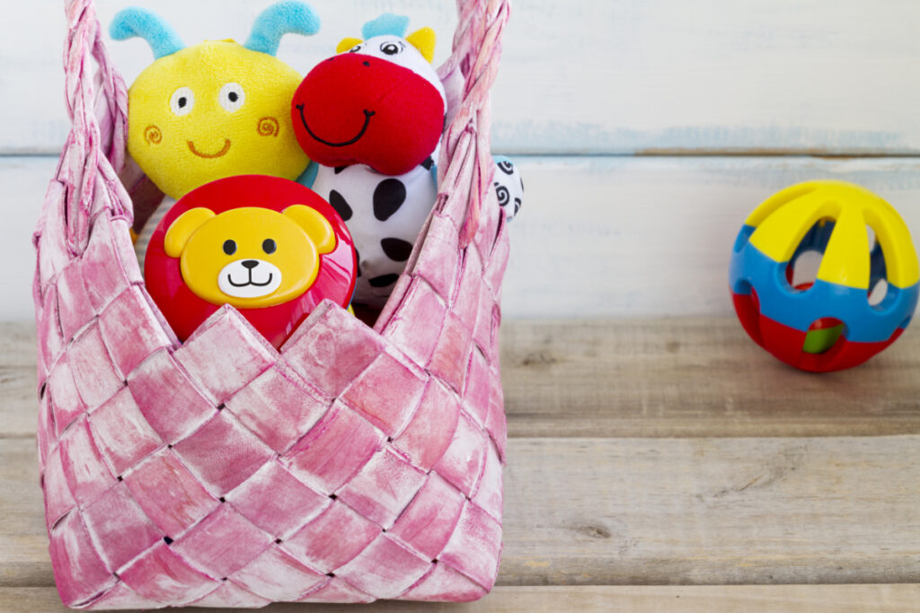 Panier de jouets et ballon - Blog d'activités pour enfants - panier rose de jouets colorés sur parquet avec ballon