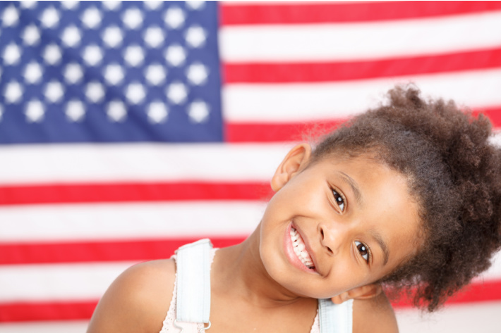 Célébration du Memorial Day pour les enfants, y compris l'artisanat - Blog d'activités pour enfants - enfant d'âge préscolaire devant un drapeau américain
