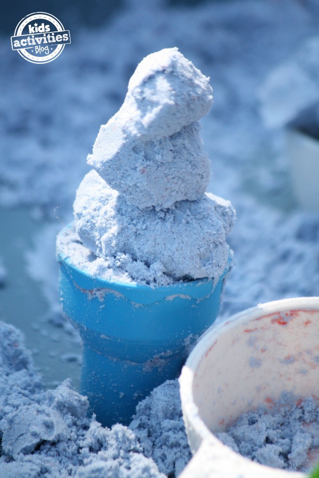 Pâte nuageuse sans danger pour les tout-petits qui ressemble à des boules de crème glacée dans un cône en plastique bleu.