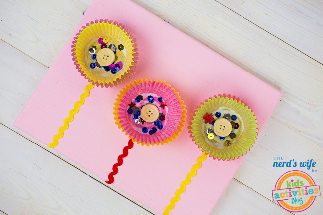 Cupcake Liner Flower Craft pour les enfants - artisanat de fleurs facile fabriqué à partir de doublures de cupcake montrées en 3 couleurs sur fond rose