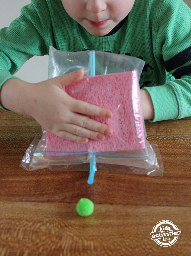 Démontrer l'expérience de pression d'air pour les enfants - sac avec éponges et paille propulsant le pompon