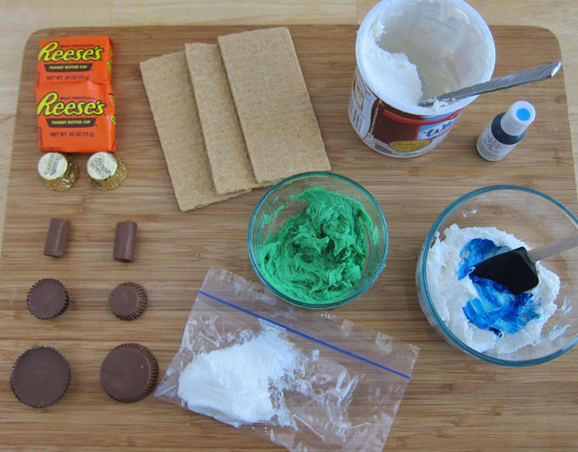 Ingrédients pour Reese's Chocolate Bunny- sur planche de bois Reese's, Tootsie rolls, biscuits Graham, colorant alimentaire bleu et vert, glaçage blanc