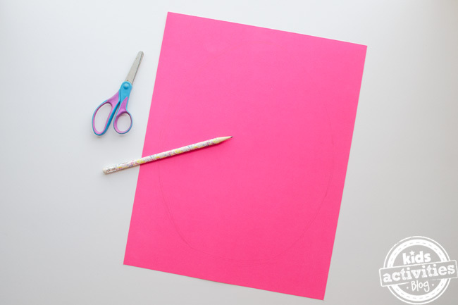 Création d'oeufs de pâques préscolaires - crayon ciseaux et feuille de papier de construction rose sur fond blanc