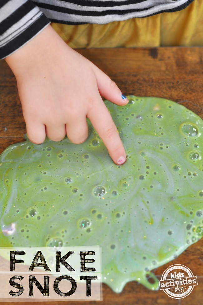 comment faire de la fausse morve - recette de slime finie montrée avec la main de l'enfant touchant la substance de slime verte - Kids Activities Blog