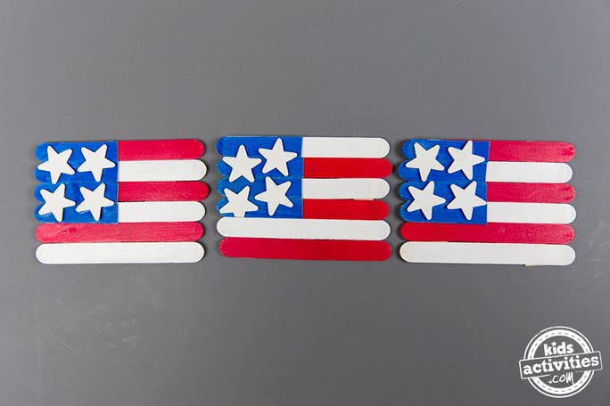 Artisanat du drapeau américain pour les enfants parfait pour le Memorial Day - Blog d'activités pour enfants - trois bâtons de popsicle artisanat du drapeau américain sur fond gris