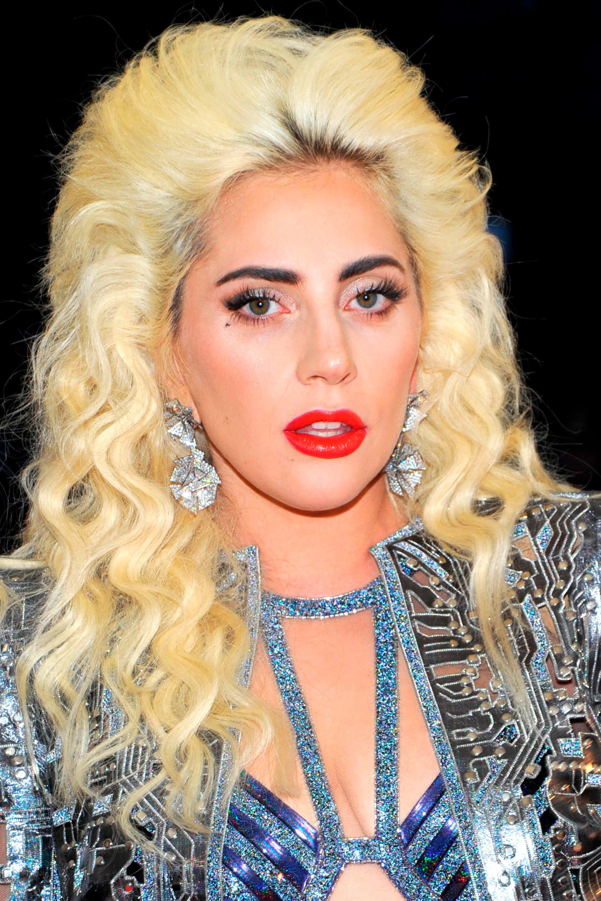 Lady Gaga avec une coiffure bouclée et une crêpe haute dans les cheveux blonds
