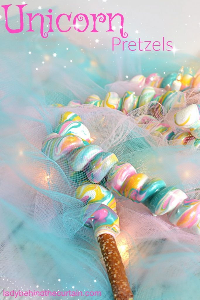 bretzels en corne de licorne présentés avec des guirlandes lumineuses et des décorations pastel claires
