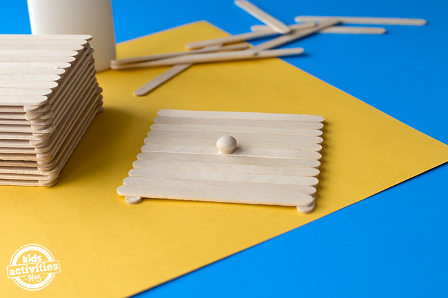 Étape 3 - Boîte artisanale classique de bâtonnets de glace - Fabriquez un couvercle en collant des bâtonnets de glace horizontalement sur deux bâtons artisanaux verticaux. N'oubliez pas le bouton ! - blog d'activités pour enfants