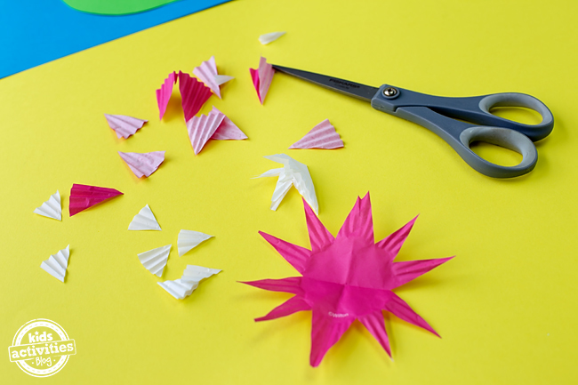 Cupcake Liner Frog Craft - Découpez la fleur en découpant des triangles dans le moule à cupcake rose.
