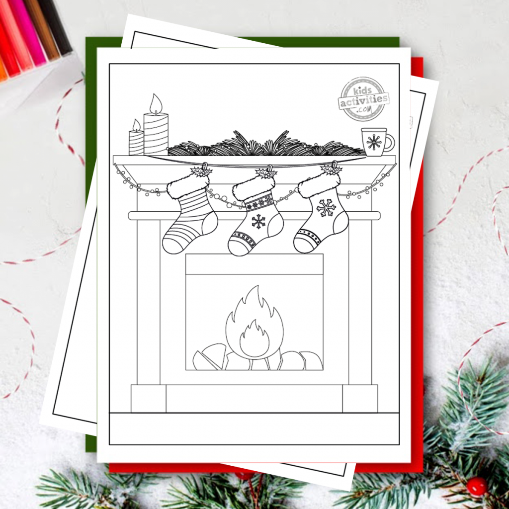 Un bas de Noël rayé, un bas avec 2 rayures et un flocon de neige, et un bas avec un gros flocon de neige et 1 rayé sont suspendus avec du houx contre un foyer chaud avec des bougies sur le dessus et une tasse de coco avec une guirlande.