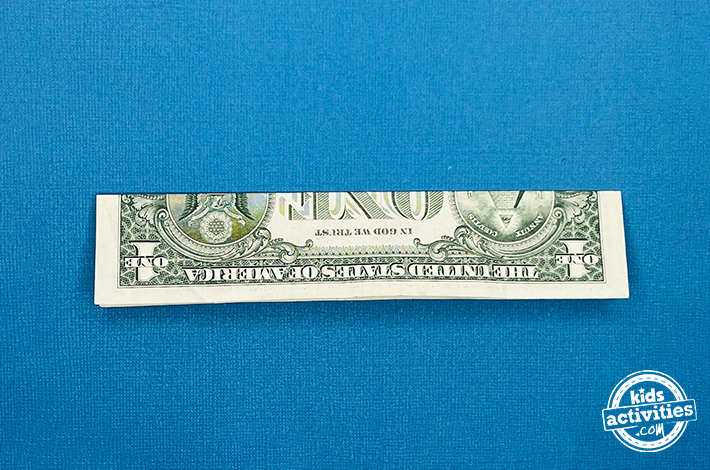 Poisson origami en forme de billet d'un dollar - étape 1 - croisez à moitié