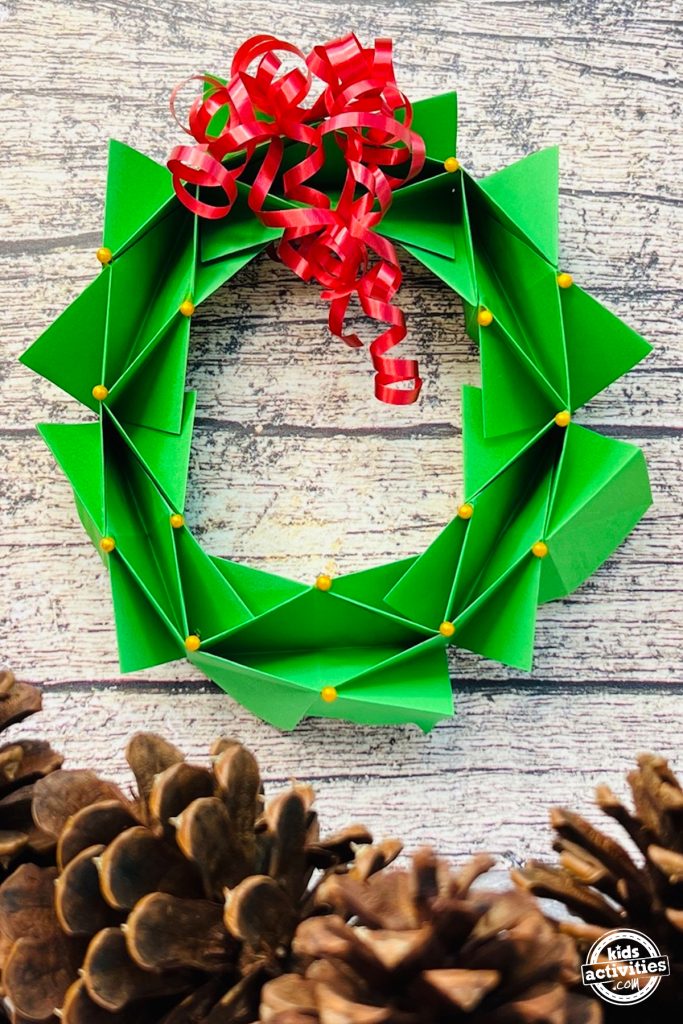 L’image montre une couronne d’origami finie avec des pommes de pin en dessous.