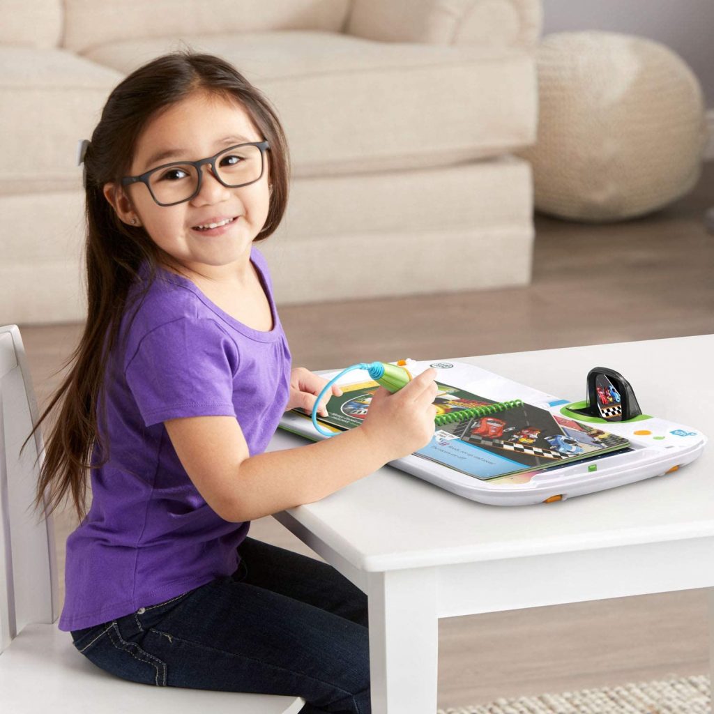 une petite fille apprend à lire à l'aide d'un livre sur les voitures de course et de son saute-mouton Leapstart 3D !