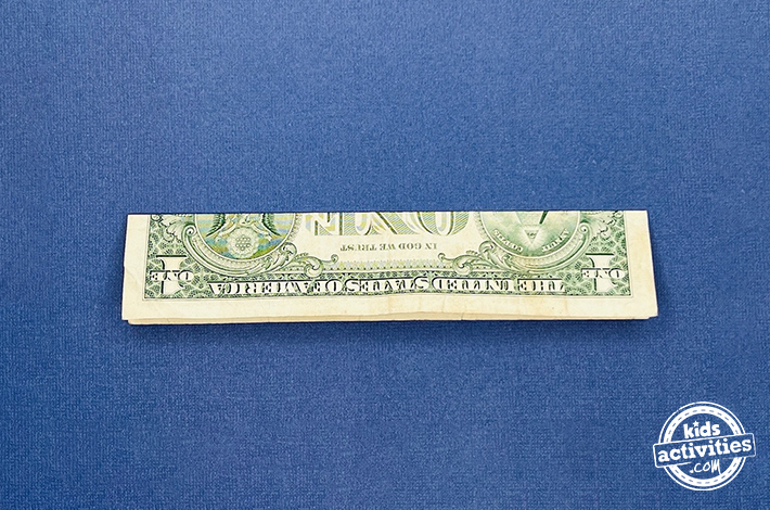 Pantalon origami en forme de billet d'un dollar - Étape 1 - pliez-le en deux dans le sens de la longueur puis en travers.