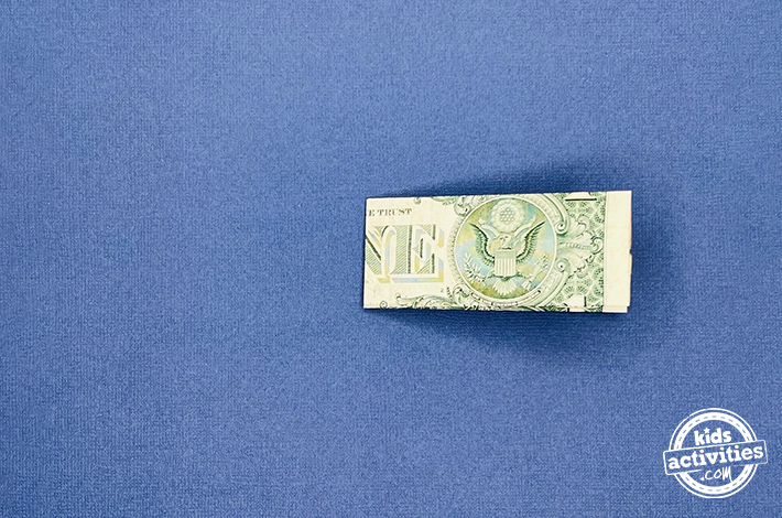 Pantalon origami billet d'un dollar - Étape 3 - Pliez le billet dans le sens de la longueur en suivant les lignes indiquées.