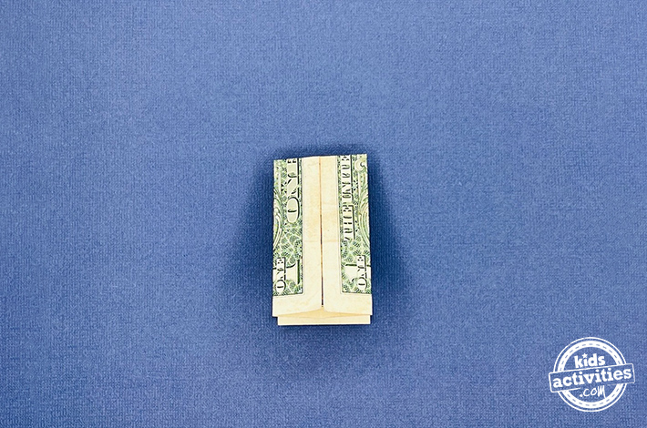 Pantalon origami en forme de billet d'un dollar - Étape 6 - Pliez la couche supérieure vers le bas, en laissant un rabat triangulaire en dessous. Retournez la forme et répétez cette étape de l’autre côté de la facture.
