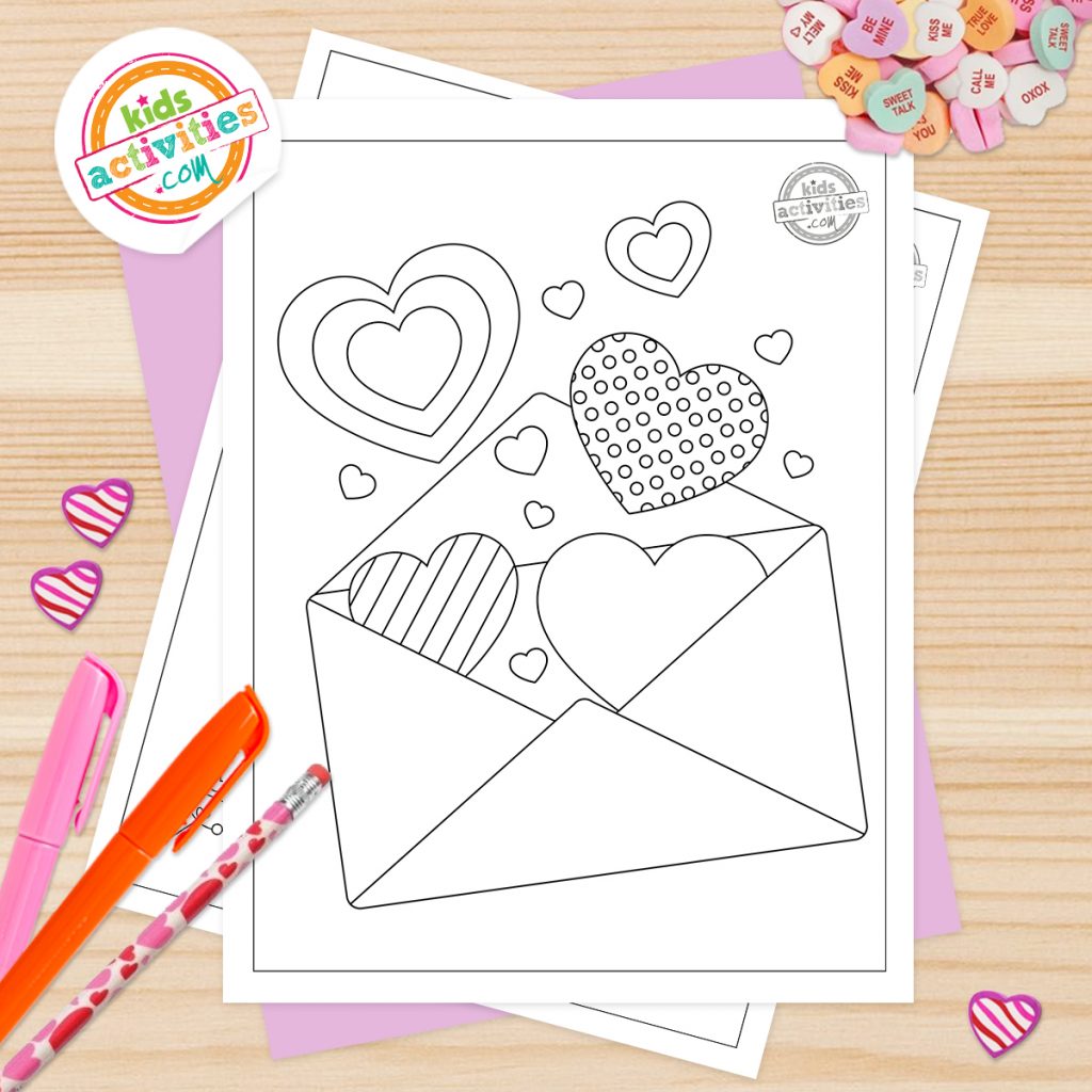 pages à colorier imprimables du cœur de la Saint-Valentin affichées sur le bureau avec des marqueurs, un crayon et des bonbons en forme de cœur de conversation