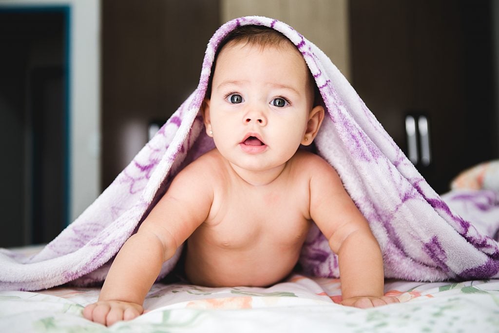 bébé regardant la caméra sur le ventre avec une serviette sur la tête