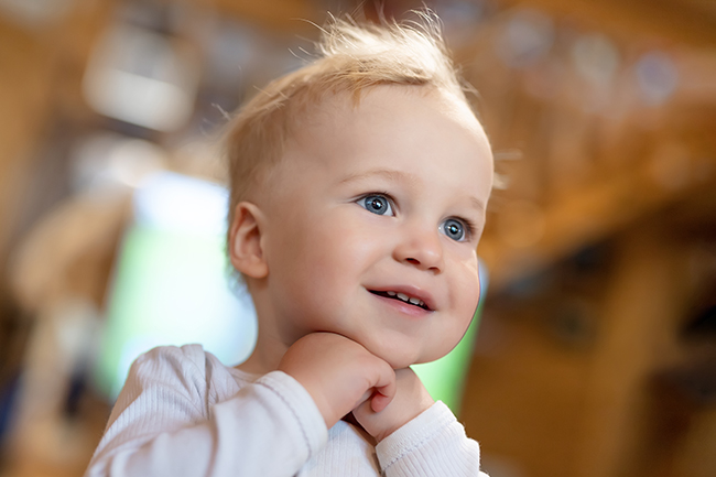 bébé regarde à travers la pièce avec les mains sous le menton
