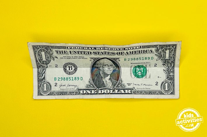 Bouteille en origami en forme de billet d'un dollar - Étape 1 - Dépliez-la pour faire un pli.  Tutoriel du blog d'activités pour enfants
