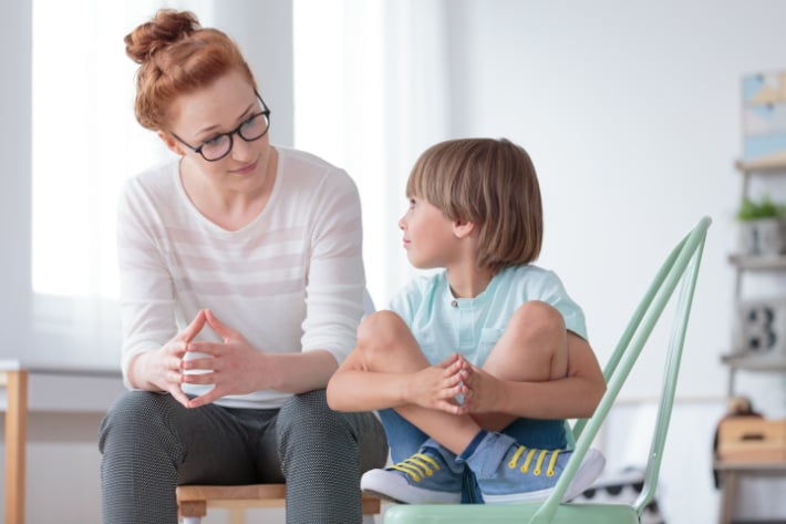 mère et enfant discutant dans une pièce légèrement colorée