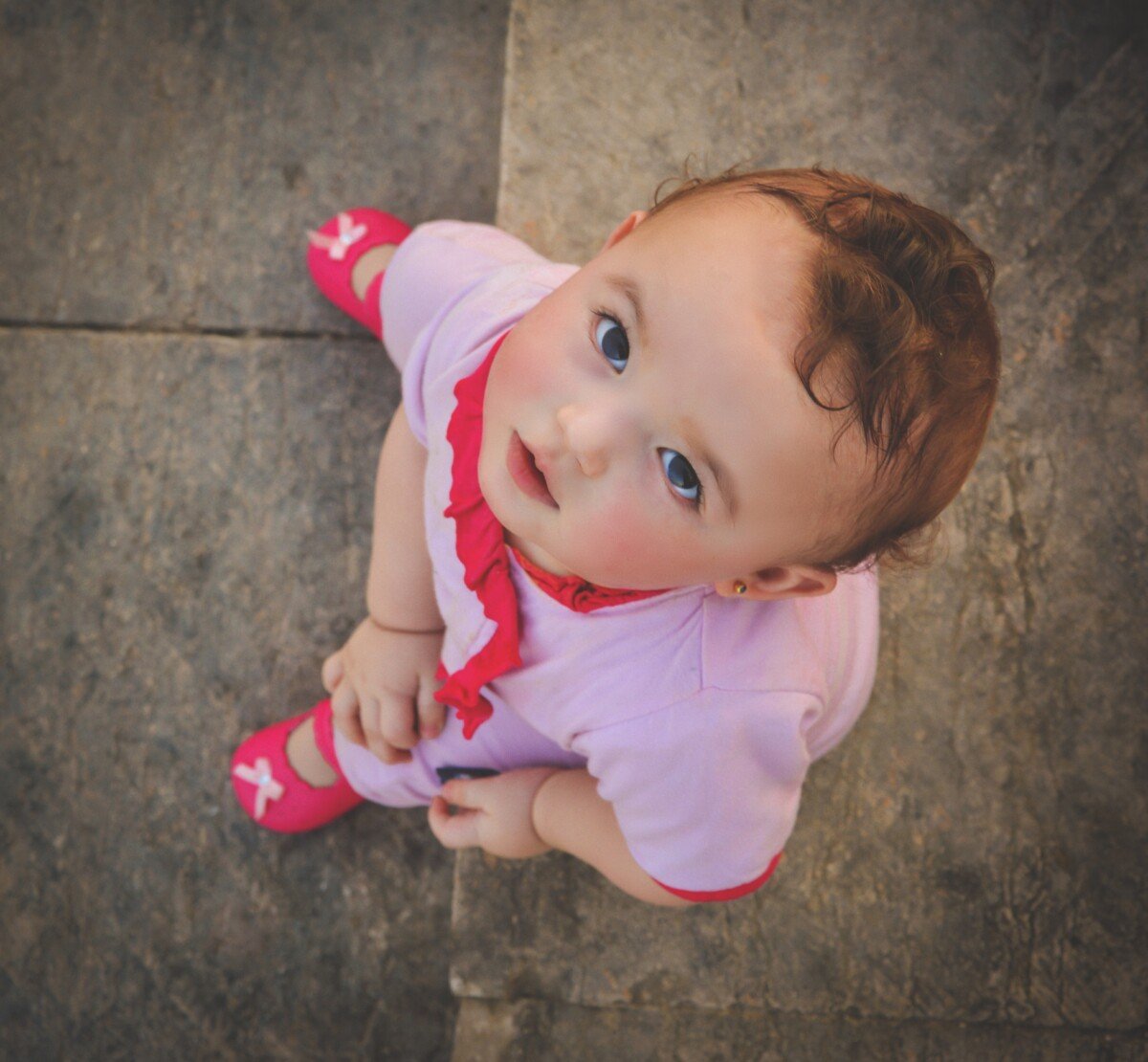 Noms de bébé des années 90 - petite fille en tenue rose et rouge levant les yeux