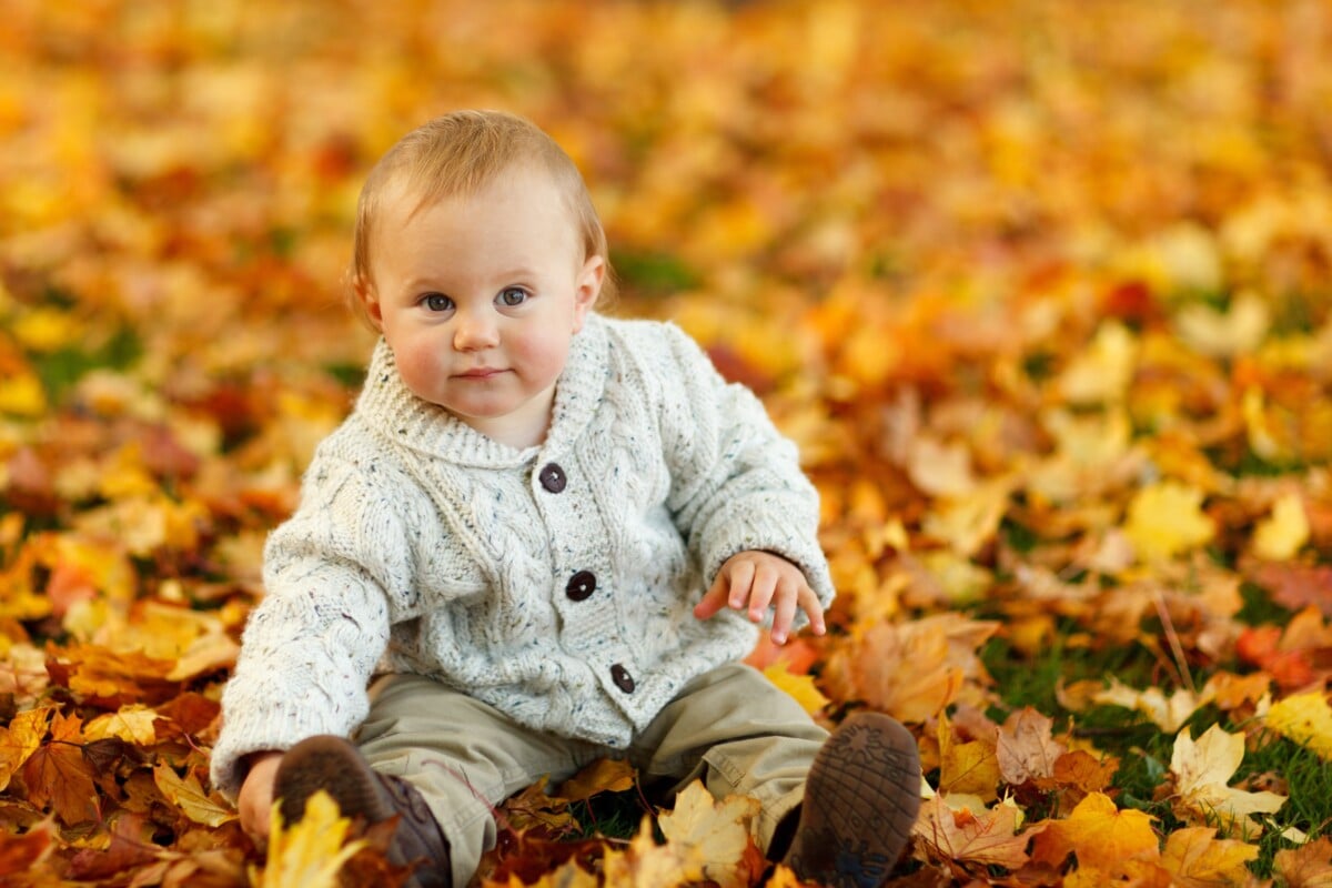 Noms de bébé des années 90 - garçon en veste au sol avec des feuilles d'or