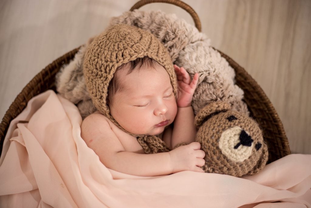 Prénoms de bébé des années 1990 : bébé dormant dans un berceau avec un ours en peluche