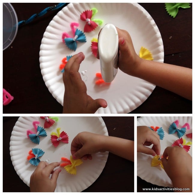 Sur la photo, étape 2 de la façon de créer des pâtes aux papillons pour les enfants d'âge préscolaire : ajouter des cure-pipes aux pâtes aux papillons et ajouter des yeux de Google.