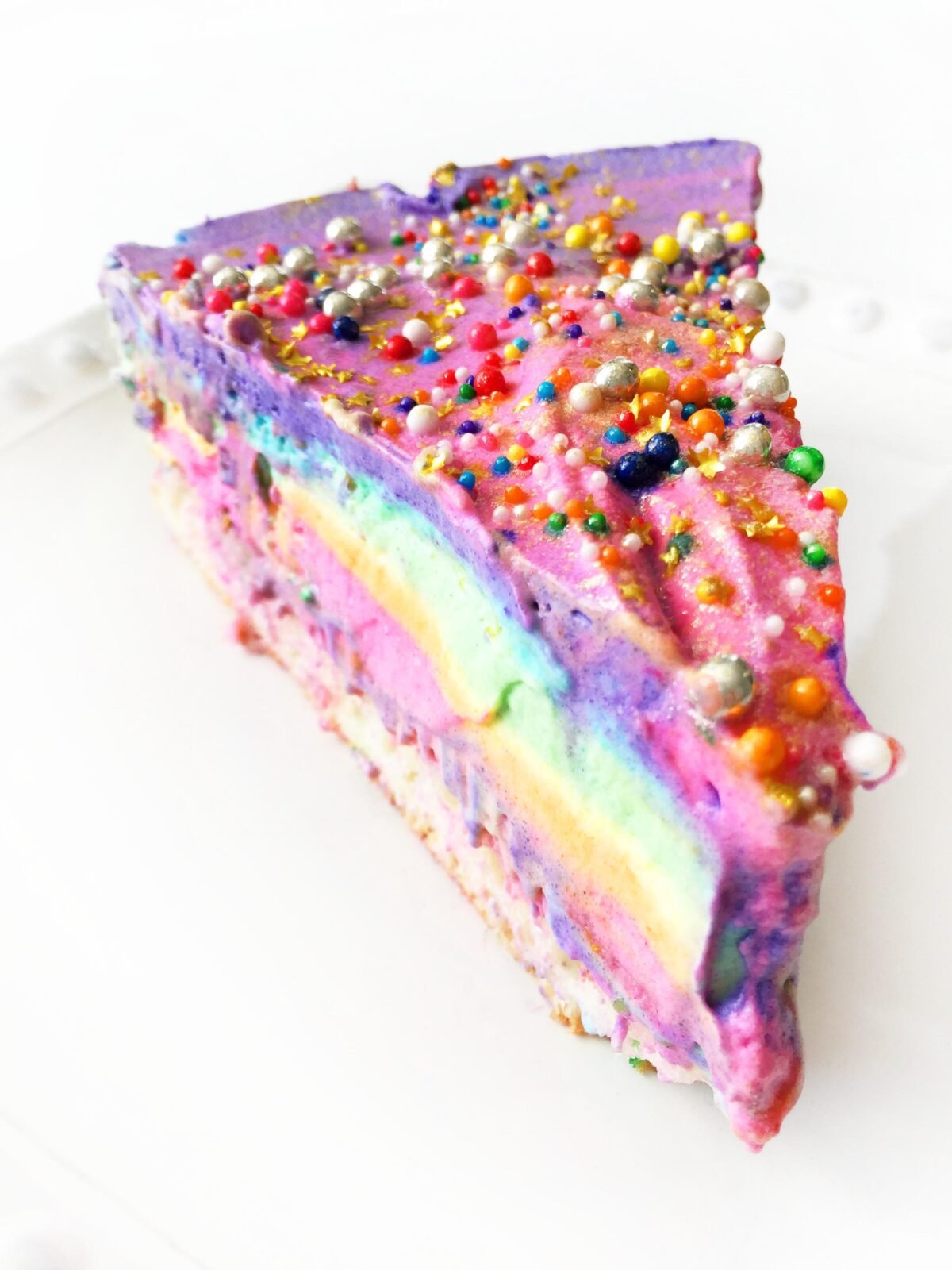 tranche de gâteau à la crème glacée fourrée arc-en-ciel et garnie de perles de sucre arc-en-ciel et de pépites