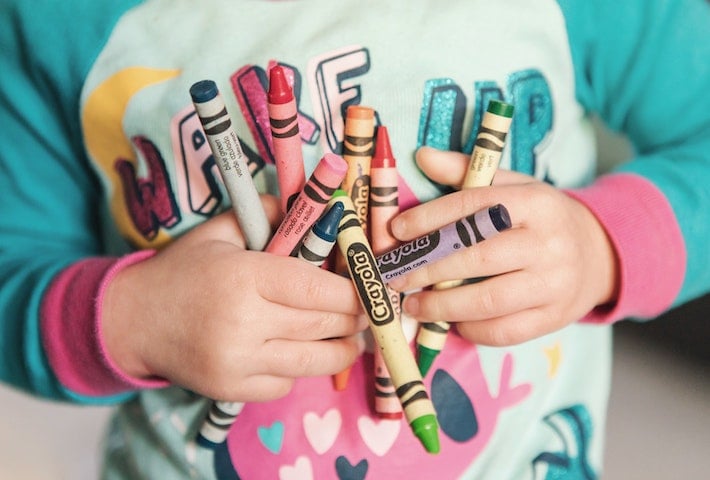 Enfant tenant des crayons - bleu, rouge, rose, jaune, vert, violet